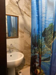 a bathroom with a sink and a shower curtain at Mang’o Hostel in Aktau