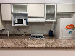 a kitchen with white cabinets and a stove and a microwave at Hermoso Depto para 4 o 6 personas in Salta