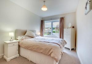 a white bedroom with a bed and a window at Castle View in Saundersfoot