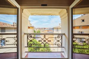 Une porte ouverte s'ouvre sur un balcon avec vue. dans l'établissement Les suites de Montigny, à Aix-en-Provence