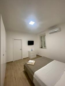 a white bedroom with a bed and a tv at GM IMMOBILIARE in Reggio di Calabria