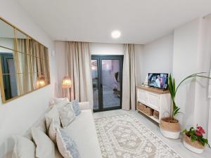 uma sala de estar com um sofá branco e uma televisão em Malvagon Isla Canela los flamencos em Isla Canela