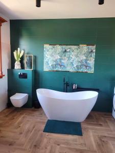 a bathroom with a white tub and a green wall at Bed and Bread in Łeba