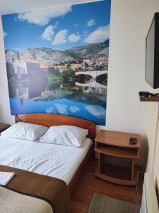 een slaapkamer met een bed met een schilderij aan de muur bij Pansion Kamin in Sarajevo