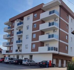 un gran edificio de apartamentos con coches aparcados frente a él en Stan_na_dan Modriča en Modriča