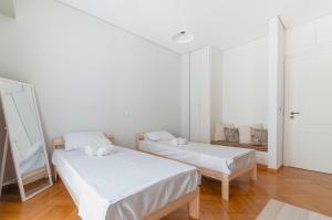 two beds in a room with white walls and wood floors at Comfortable 2 BD apartment close to Athens archeological museum in Athens