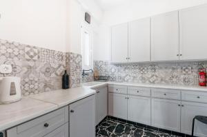 a kitchen with white cabinets and a tile wall at Comfortable 2 BD apartment close to Athens archeological museum in Athens