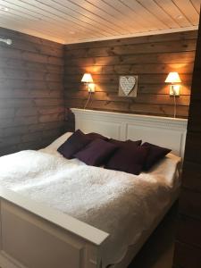 un letto in una camera con pareti in legno e 2 lampade di På solsiden av Gaustatoppen a Tuddal