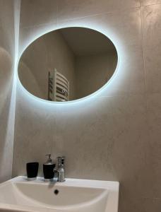 a bathroom with a sink and a round mirror at VIP Апартаменти подобово in Lutsk