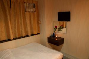 um quarto de hotel com uma cama e uma televisão em Blue Sky Hotel em Hong Kong