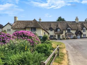 una casa de campo con flores frente a una carretera en Karslake Cottage, en Winsford