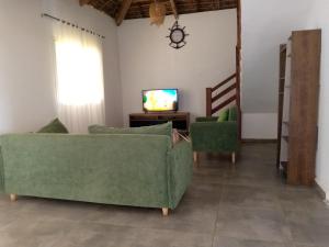 un salon avec deux canapés verts et une télévision dans l'établissement La Résidence Tiako, à Ambondrona