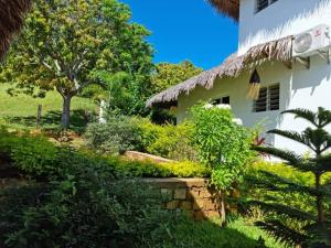 une maison avec un toit de chaume et un jardin dans l'établissement La Résidence Tiako, à Ambondrona