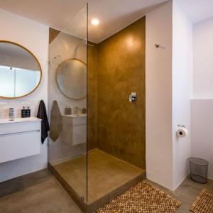 a bathroom with a shower with a sink and a mirror at Eleven in Plettenberg Bay