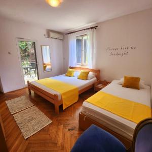 een kamer met 2 bedden met gele lakens en een raam bij A step to the sea-Na korak do mora-Studio apartments Bela kuća in Rafailovici