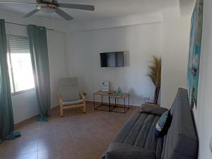 Una sala de estar con un sofá y un televisor. en Apartamento Bajo en Valdelagrana, Primera Línea de Playa, en El Puerto de Santa María