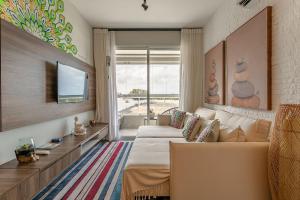 Sala de estar con 2 camas y TV en Apto no cond Thai Beach Home Spa frente mar TBS106, en Florianópolis