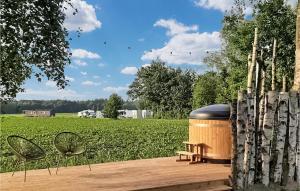 um deque de madeira com um barril e duas cadeiras e um campo em Stunning Apartment In Schoonloo With Wifi em Schoonloo