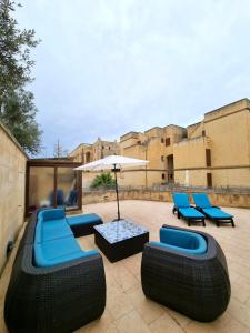 un patio con sillas azules y una sombrilla en Fort Chambray Gozo, en Għajnsielem