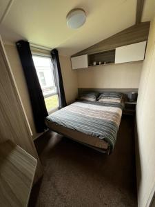 a small bedroom with a bed and a window at Aberlady75 in Port Seton