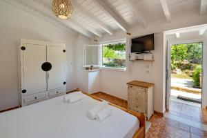 a bedroom with a white bed and a television at Aphrodite's hidden gem on Paxos island in Velianitátika