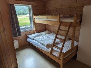 a bunk bed in a log cabin with a window at Solstrand Camping in Vigeland