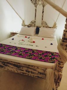 uma cama num quarto com flores em Lalasalama B&B em Watamu