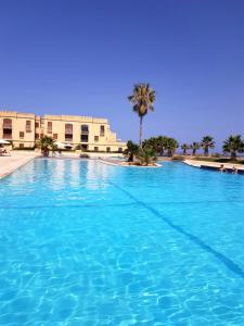 una gran piscina con palmeras en el fondo en Fort Chambray Gozo, en Għajnsielem