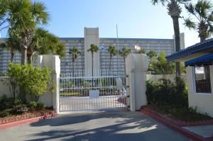 a white gate in front of a building with palm trees at The Summit Condominiums in Panama City Beach