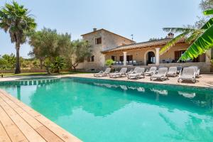 a swimming pool with lounge chairs and a house at Finca Es Figueral in Campos