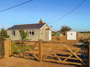 a wooden fence in front of a house at Curlew Cottage in Thorpe Saint Peter