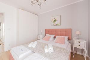 - une chambre dotée d'un lit avec des oreillers blancs et roses dans l'établissement Posesja Kapitańska Apartament ok 100 m do plaży, à Grzybowo