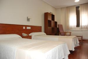a hotel room with two beds and a chair at Apartahotel FC Catedral in León