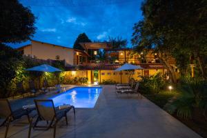 a pool with chairs and umbrellas in front of a house at Pousada Espaço do Sagui - Taipu de Fora in Barra Grande