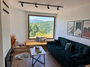 a living room with a green couch and a large window at Villa Luce in Kolašin