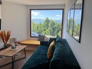 a living room with a blue couch and a large window at Villa Luce in Kolašin