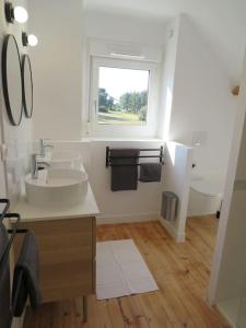 a white bathroom with a sink and a window at Maison - plage à pied in Frehel