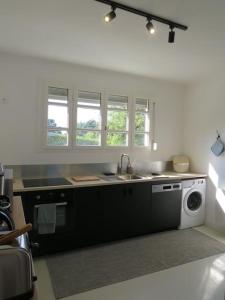 a kitchen with a sink and a washing machine at Maison - plage à pied in Frehel