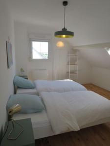 1 dormitorio con 2 camas blancas y ventana en Maison - plage à pied, en Fréhel