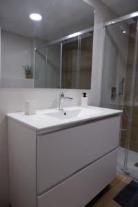 a white bathroom with a sink and a mirror at Amplio apartamento con piscina al lado de la playa in Platja d'Aro