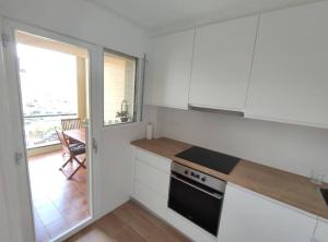a kitchen with white cabinets and a stove top oven at Amplio apartamento con piscina al lado de la playa in Platja d'Aro