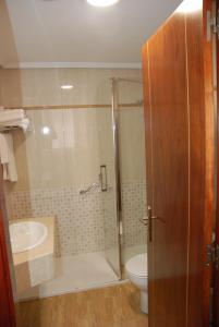 a bathroom with a shower and a toilet and a sink at Apartahotel FC Catedral in León