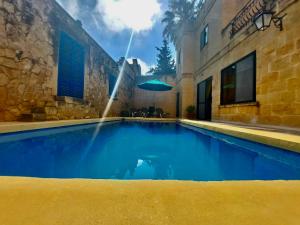 a swimming pool with a fountain in front of a building at MJ Farmhouse B&B in Xagħra