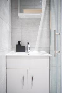 uma casa de banho com um lavatório branco e um espelho. em Stylish Studios with Ensuite, Separate Kitchen, and Prime Location in St Helen em Saint Helens