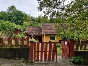 una casa detrás de una valla roja con una puerta roja en Csukavölgyi Apartman, en Visegrád