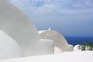 a white building with the ocean in the background at OUTOPOIA CAVE STUDIOS in Oia