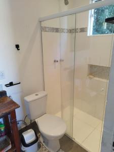 a bathroom with a toilet and a glass shower at Loft Monte Alegre Village in Monte Alegre do Sul