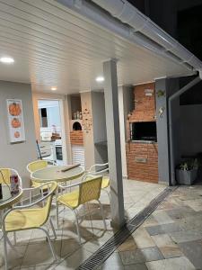 eine Terrasse mit einem Tisch und Stühlen sowie eine Küche in der Unterkunft Casa de praia em Riviera no Módulo 21 in Bertioga