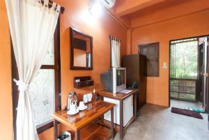 a living room with orange walls and a tv and a table at Namkhong Guesthouse and Resort in Chiang Khong