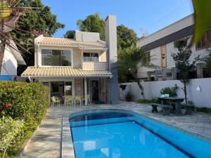 eine Villa mit einem Pool vor einem Haus in der Unterkunft Casa de praia em Riviera no Módulo 21 in Bertioga
